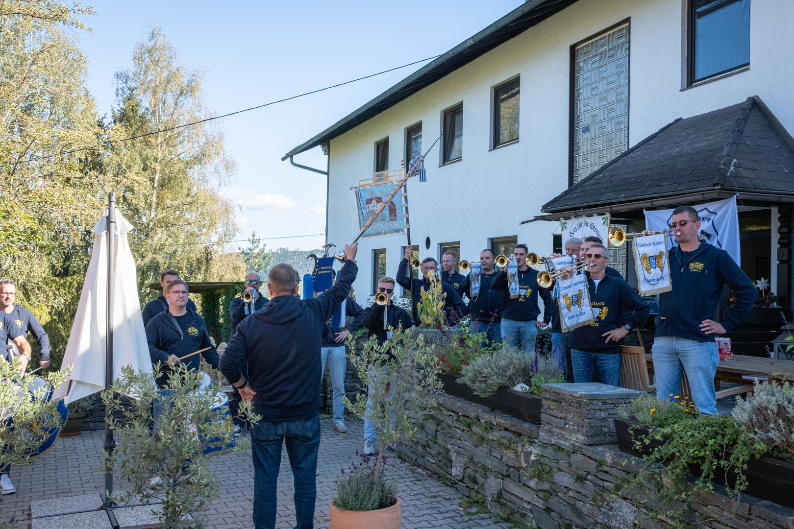 Blaskapelle spielt vor einem Haus in Österreich mit Fahnen und Trommeln